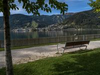 the park bench is located near the road on a sunny day by the water,