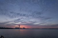 the sun sets on the skyline of a city over the water with a body of water