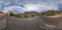 a curved road stretches out into a blue sky with white clouds overhead and some rocks