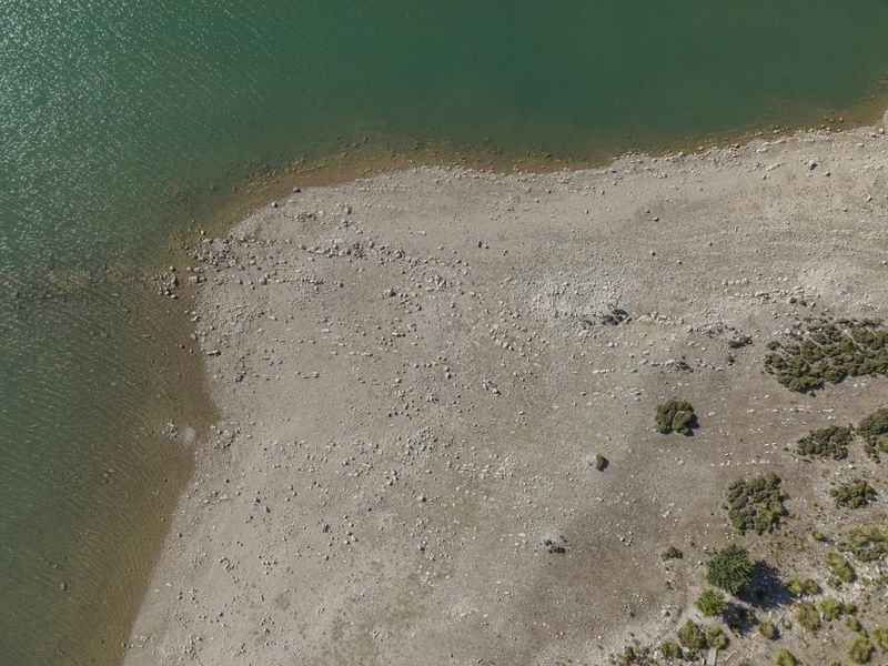 Aerial view of people wading in the water near shore rocks and sand in ...